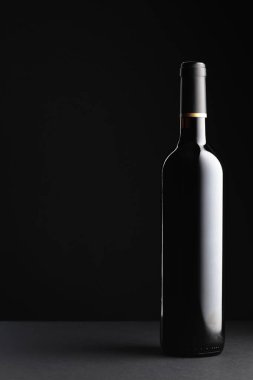Siyah arka planda açılmamış bir şişe kırmızı şarap. Boşluğu kopyala.
