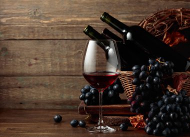 Red wine and blue grapes. Wine and grapes in a vintage setting on an old wooden table.