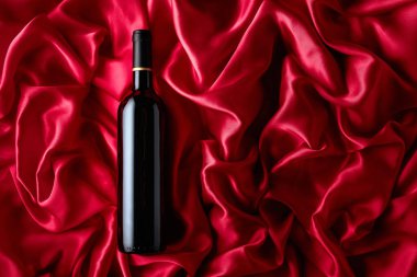 Bottle of red wine on a satin background. Top view.