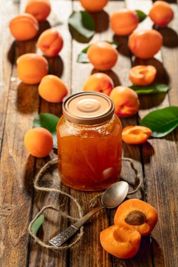 Cam kavanozda kayısı reçeli ve eski ahşap bir masada taze meyve..