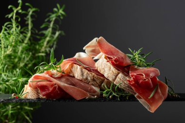 Siyah arka planda prosciutto ve biberiyeli Ciabatta. Geleneksel İtalyan atıştırması.
