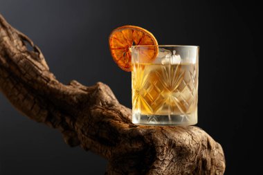 Eski usul buzlu ve kurutulmuş portakal dilimli bir kokteyl eski ahşap bir çıkmazda. Kopyalama alanı olan siyah arkaplan.