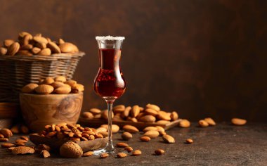 Alkolik İtalyan likörü Amaretto. Şarap masasında badem fıstığı var. Boşluğu kopyala.