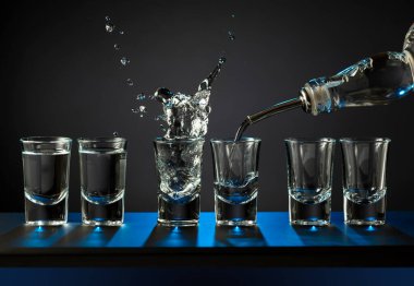 Alkolik votka kadehleri ya da küçük bardaklarda sert içkiler. Barmen sert ruhu bardaklara doldurur, servis ve içecekler hakkında konsept yapar. Boşluğu kopyala.