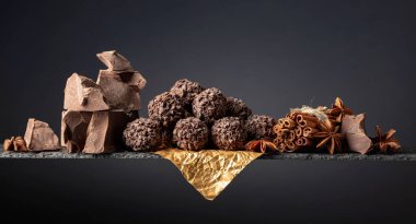 Çikolatalı trüf, kırık çikolata ve baharatlı. Çikolata, tarçın çubukları ve koyu bir arka planda anason. Boşluğu kopyala.