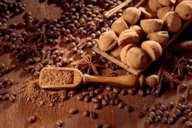 Çikolatalı trüf mantarı ve kakao tozlu tahta kaşık. Eski ahşap bir masada tarçın, anason ve kahve çekirdekli lezzetli çikolatalı trüf..