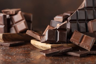 Kahverengi bir arka planda kırık acı ve sütlü çikolatalar..