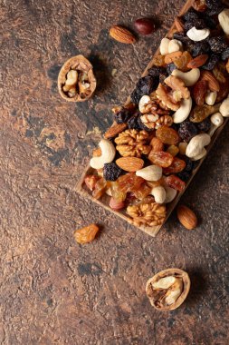Kahverengi bir arka planda fındık ve kuru üzüm karışımı. Sunulan kuru üzüm, ceviz, fındık, fındık, ceviz, ceviz ve badem. Üst görünüm.