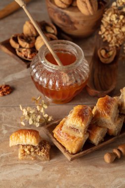 Bej arka planda ceviz ve bal olan baklava. Geleneksel Doğu Çölü ahşap tabakta.