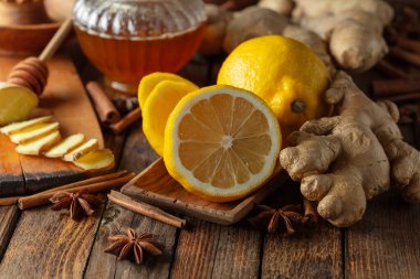 Zencefilli çay hazırlamak için gerekli malzemeler. Zencefil, limon, bal, anason ve tarçın çubukları eski bir mutfak masasında..