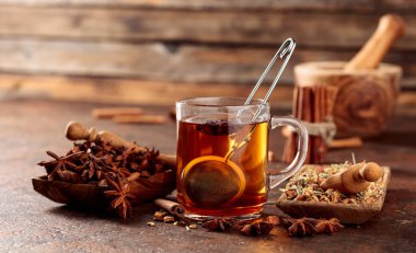 Tarçınlı, anasonlu ve kurutulmuş otlu Noel çayı. Eski kahverengi bir masada, ahşap tabaklarda baharatlı bitki çayı..