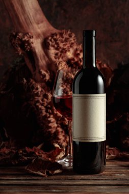 Eski ahşap bir masada şişe ve bir bardak kırmızı şarap. Fotokopi alanı olan eski bir şişede.