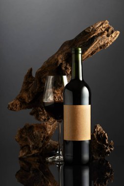 Eski boş etiketli bir şişe ve bir kadeh kırmızı şarap. Arka planda eski yıpranmış bir pürüz var. Pahalı şarap kavramı.