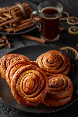 Kanelbullar - İsveç tarçınlı çörekler ya da dürümler. Siyah taş bir masada taze pişmiş çörekler..