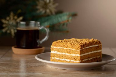 Noel ağacının arka planında katmanlı ballı kek. Geleneksel Noel pastası. Boşluğu kopyala.