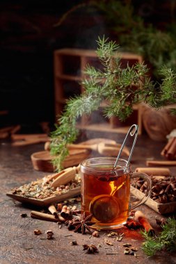 Tarçınlı, anasonlu ve kurutulmuş otlu Noel çayı. Eski bir masada ardıç dallı bitki çayı..
