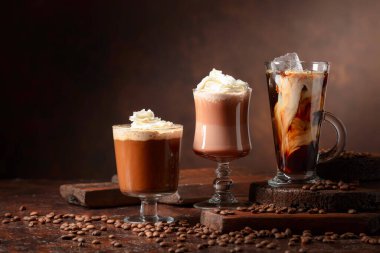 Kahverengi arka planda kremalı kahve ve çikolata içecekler..