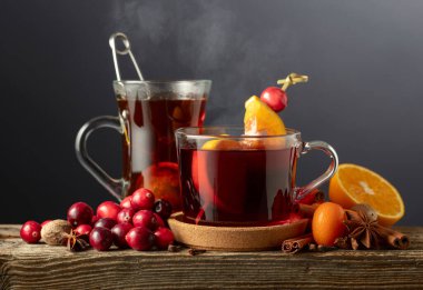 Karanlık bir arka planda baharat, kızılcık ve turunçgil meyveli sıcak kış içecekleri. Boşluğu kopyala.