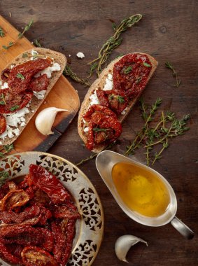 Ev yapımı kurutulmuş domatesli ve süzme peynirli sandviç. Güneş yağında kurutulmuş domates kekik ve eski ahşap bir masada sarımsak. Üst görünüm.