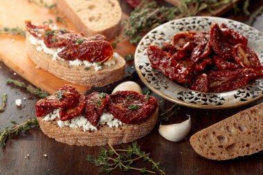 Ev yapımı kurutulmuş domatesli ve süzme peynirli sandviç. Güneş yağında kurutulmuş domatesler kekik ve eski ahşap bir masada sarımsak..