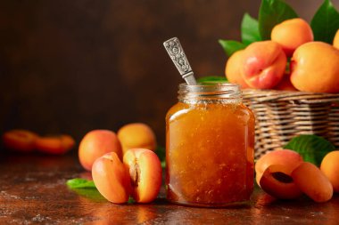 Cam kavanozda kayısı reçeli ve kahverengi bir masada taze meyve. Boşluğu kopyala.