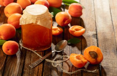 Cam kavanozda kayısı reçeli ve eski ahşap bir masada taze meyve..