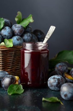 Lacivert arka planda erik reçeli ve taze böğürtlen. Mutfak masasında reçelli olgun erikler..