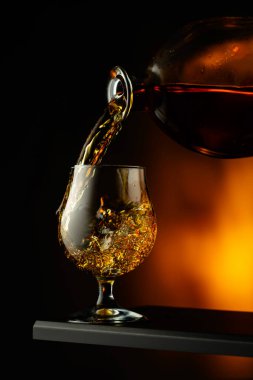 Bardağa konyak ya da brendi dökülüyor. Koyu bir arka planda brendi içicisi.