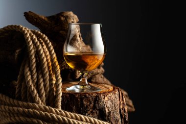 Eski bir kütüğe konyak ve ip. Viski, konyak ya da koyu bir arka planda konyak..