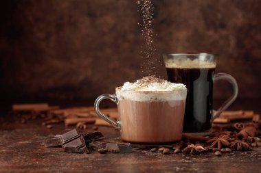 Çikolata kırıntıları ve bir bardak koyu kahve serpiştirilmiş kremalı sıcak çikolata..