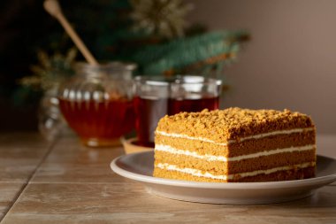 Noel ağacının arka planında katmanlı ballı kek. Geleneksel Noel pastası. Boşluğu kopyala.