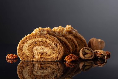 Siyah yansıtıcı arka planda cevizli tatlı. Kahverengi şeker, ceviz ve kremalı kek. Boşluğu kopyala.