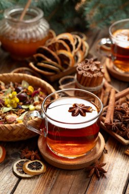 Tarçın, anason ve kuru narenciye dilimli Noel çayı. Eski ahşap bir masada malzemeli bitki çayı..