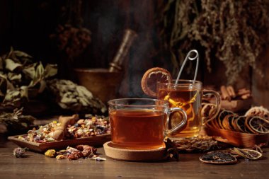 Çeşitli kurutulmuş otlar, çiçekler ve baharatlarla dolu bir fincan bitki çayı. İçindekilerle çay ve kurutulmuş narenciye..