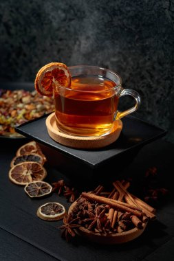 Bir fincan bitki çayı ve siyah seramik bir masada kurutulmuş portakal dilimleri..