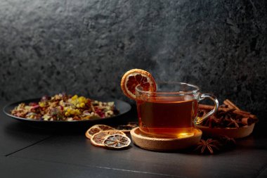 Bir fincan bitkisel çay ve siyah seramik bir masada kurutulmuş portakal dilimleri. Boşluğu kopyala.