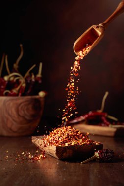 Biberler ahşap bir tabağa dökülür. Eski ahşap bir masada kırmızı biber ve kırmızı biber..