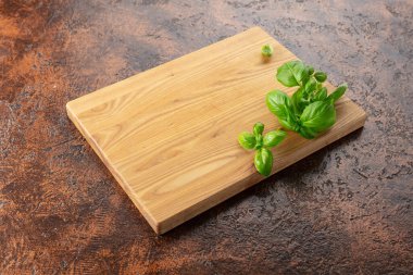 Kahverengi mutfak masasında fesleğen ve tahta kesme. Mutfak geçmişi. Boş tahta kesme tahtası, ürün görüntüleme alanı.