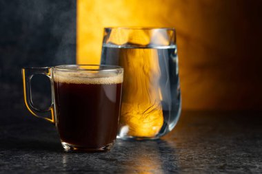 Siyah taş bir masada espresso ve bir bardak soğuk su. Boşluğu kopyala.