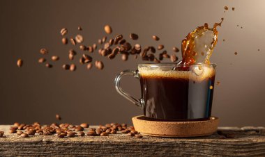 Eski bir tahtanın üzerinde cam bardakta sade kahve. Kavrulmuş kahve çekirdekleri hareket halinde. Boşluğu kopyala.