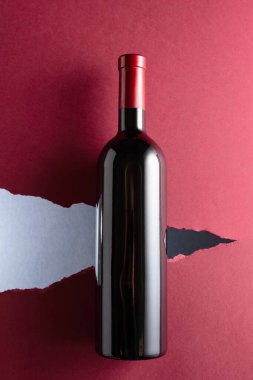 Koyu kırmızı arka planda bir şişe kırmızı şarap. Üst görünüm.