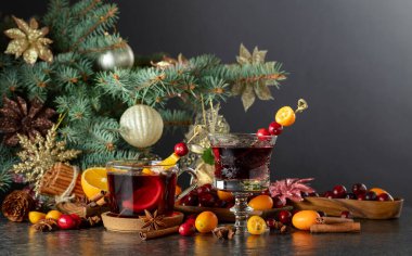 Noel ağacının arka planında baharat, kızılcık ve narenciye içeren kırmızı Noel içecekleri. Boşluğu kopyala.