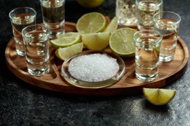 Siyah bir masada tuz ve limon dilimli altın tekila..