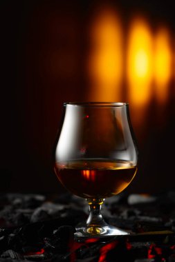 Yanan bir kömürün üzerinde bir fırt brendi. Sert alkollü içecekler kavramı. Boşluğu kopyala.