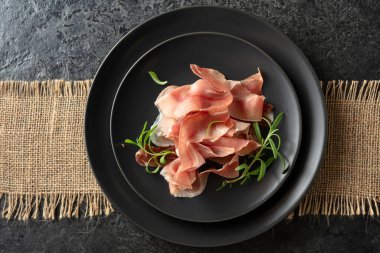 Prosciutto ve biberiye siyah bir masada. Üst görünüm. 