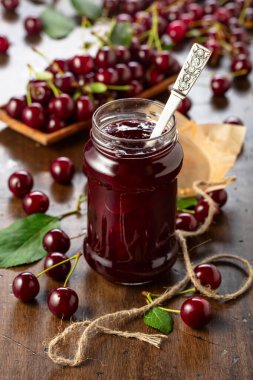 Vişne reçeli ve taze böğürtlen eski ahşap bir masada yapraklarla.