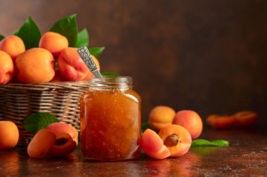 Cam kavanozda kayısı reçeli ve kahverengi bir masada taze meyve. Boşluğu kopyala.