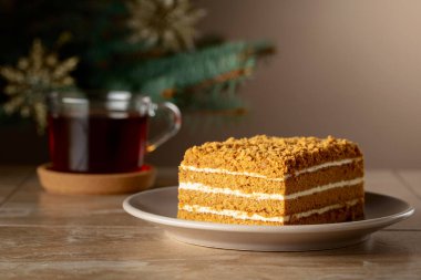 Noel ağacının arka planında katmanlı ballı kek. Geleneksel Noel pastası. Boşluğu kopyala.