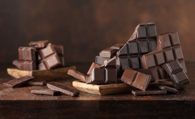 Kahverengi bir arka planda kırık acı ve sütlü çikolatalar..