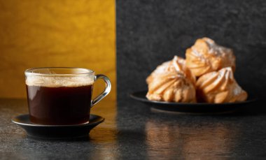 Cam bardakta sade kahve ve siyah taş masada kremalı kek. Boşluğu kopyala.